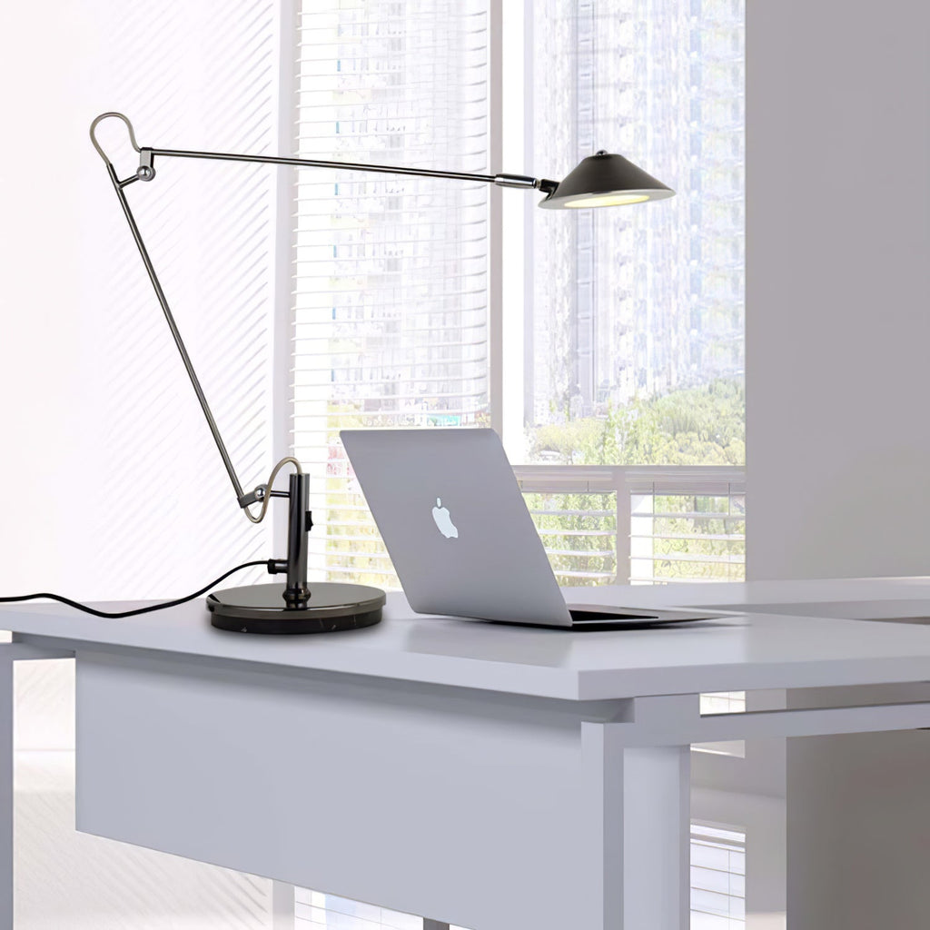 A Clérachic black arm lamp beside a laptop on a white desk, its arm held out and shade lit, with a view of city blocks.