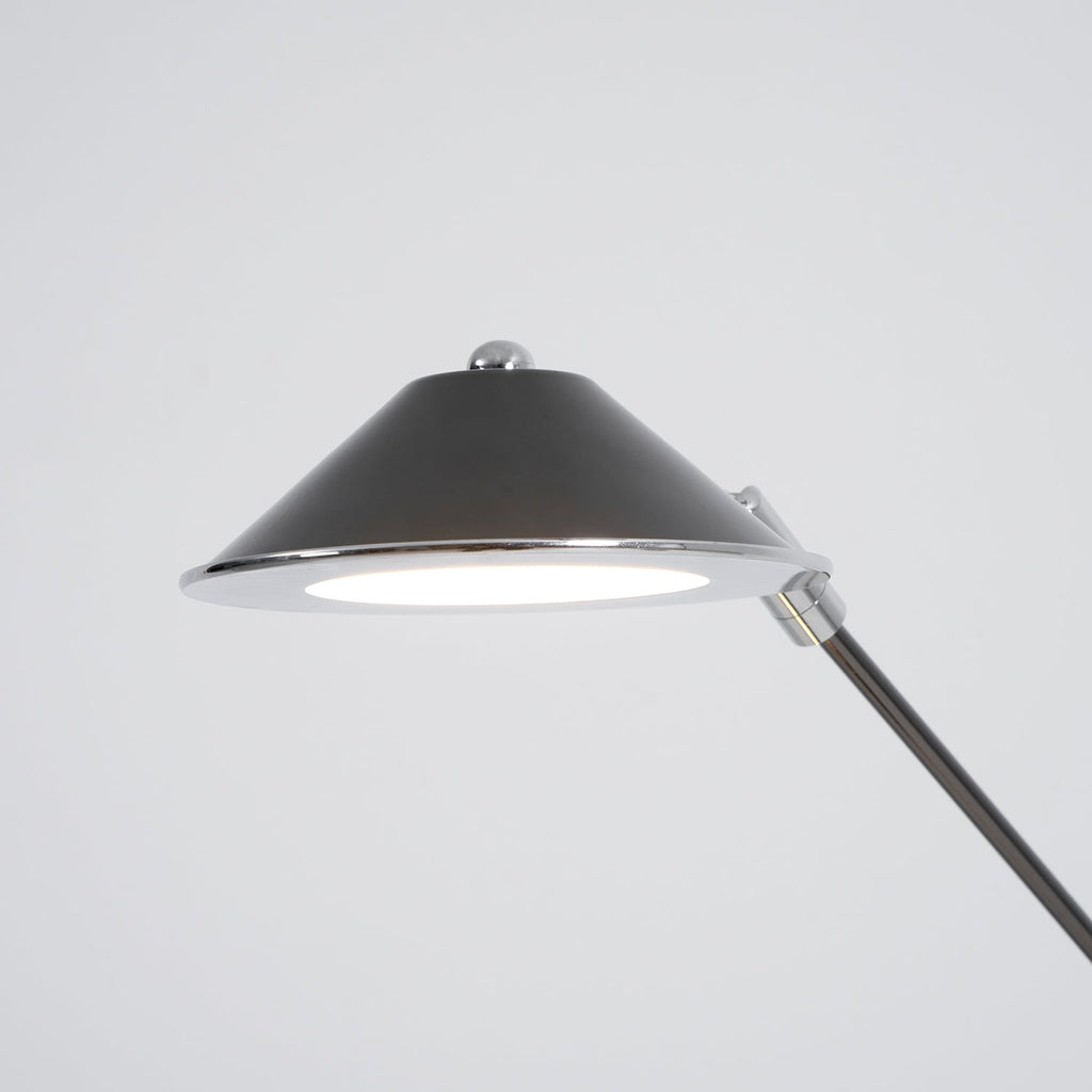 Close view of the underside of this Clérachic lamp shade, a black cone with a chrome rim and a bright, flat LED panel.