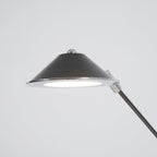 Close view of the underside of this Clérachic lamp shade, a black cone with a chrome rim and a bright, flat LED panel.