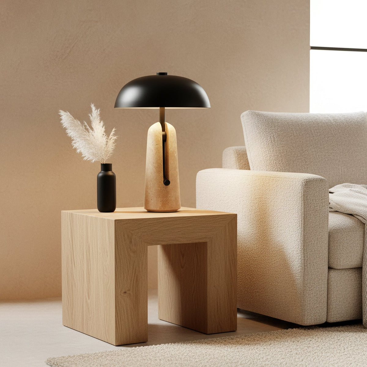 A black-domed Clérachic table lamp on a pale oak side table, with dried pampas grass in a black vase beside it.