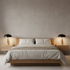 Two Clérachic table lamps glow on matching floating oak nightstands either side of a low oak bed with pale linen.