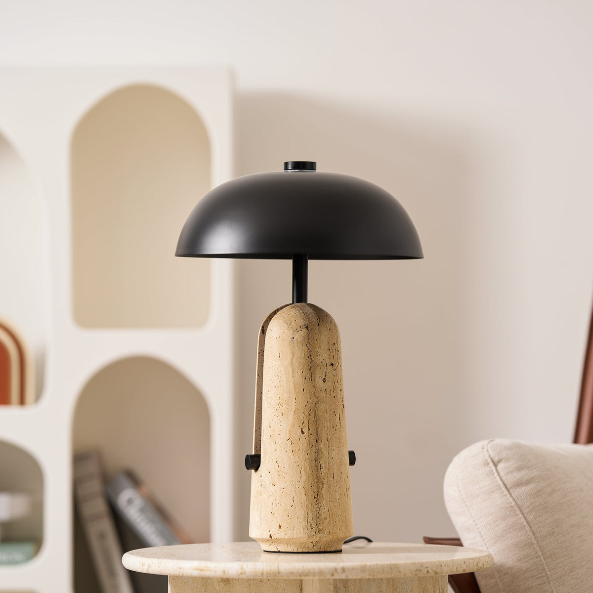 Close view of the dome shade and the ridged travertine base on this Clérachic table lamp, on a travertine side table.