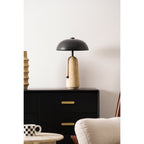 This Clérachic table lamp is small in the frame on a black chest of drawers, with a checked cup and a cream armchair below.