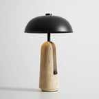 Slightly lower angle of this Clérachic table lamp, the black dome shade wider than its narrow travertine base.