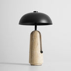Slightly raised angle showing the inside of the black dome shade on this Clérachic table lamp above its travertine base.