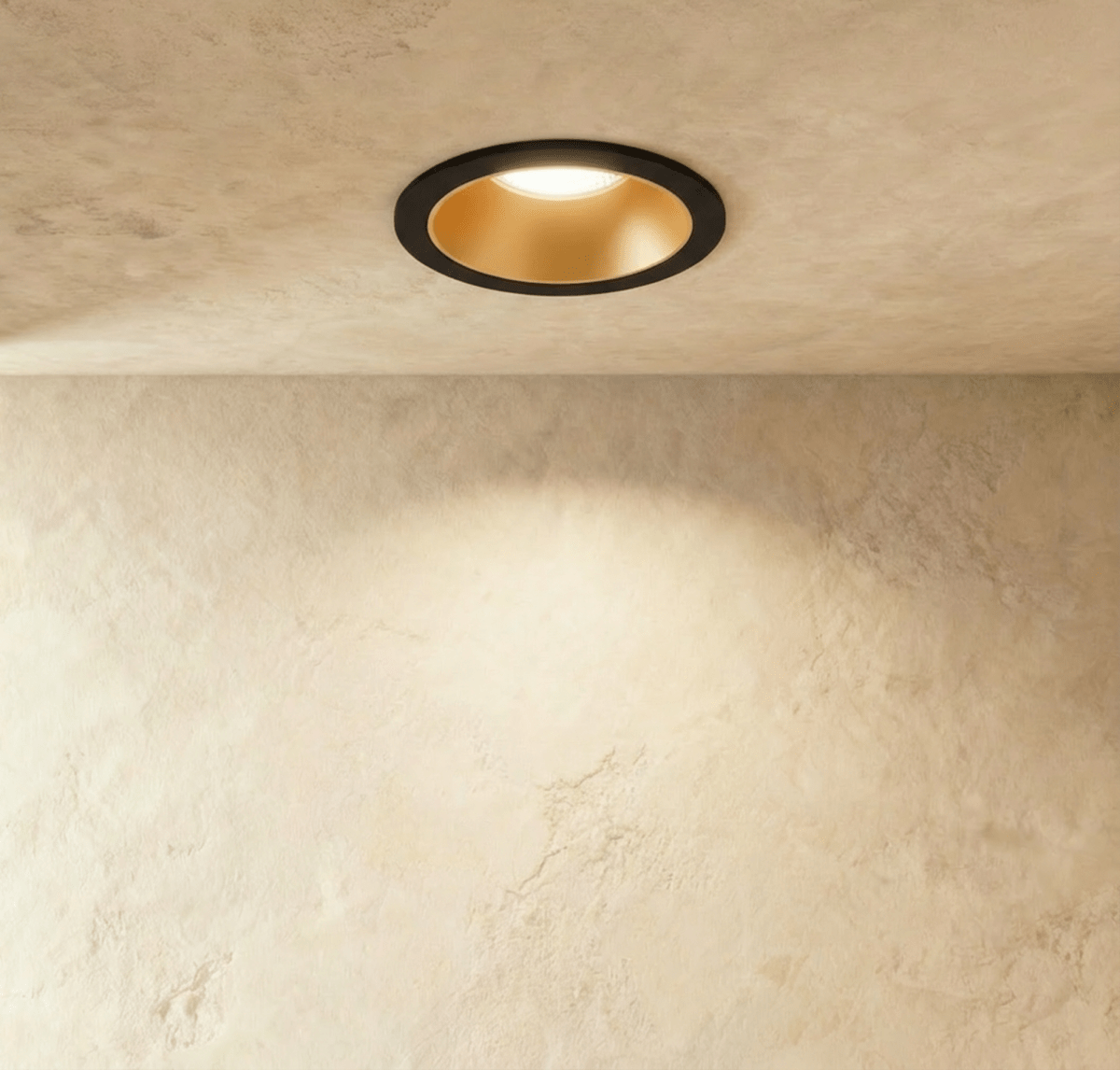 The Clérachic recessed downlight in black and gold, its gold baffle glowing warm white against a plaster ceiling.
