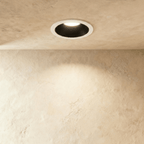 The Clérachic recessed downlight in black and white, its black baffle glowing warm white within a white trim ring.