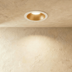 The Clérachic recessed downlight in white and gold, its gold baffle glowing warm white within a white trim ring.