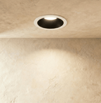 The Clérachic recessed downlight in black and white, its round trim glowing warm white against a plaster wall.