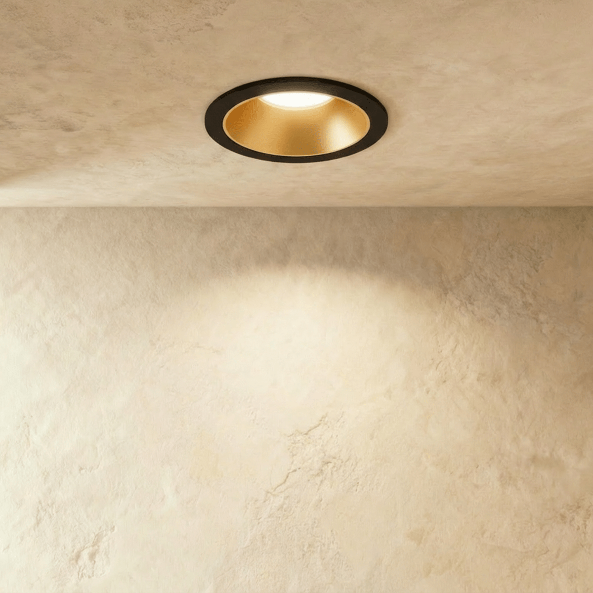 The Clérachic recessed downlight in black and gold, its gold baffle glowing warm white against a plaster ceiling.