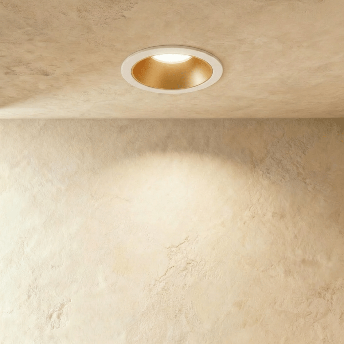 Close angle of the Clérachic white and gold recessed downlight, its baffle glowing warm white overhead.