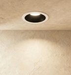 The Clérachic recessed downlight in black and white, its round trim glowing warm white against a plaster ceiling.