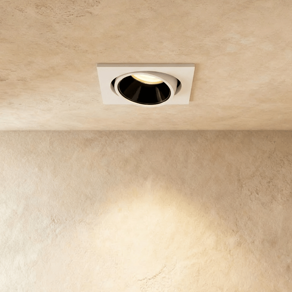 The Clérachic recessed downlight in white, its tiltable black-lined head glowing warm white against a plaster ceiling.