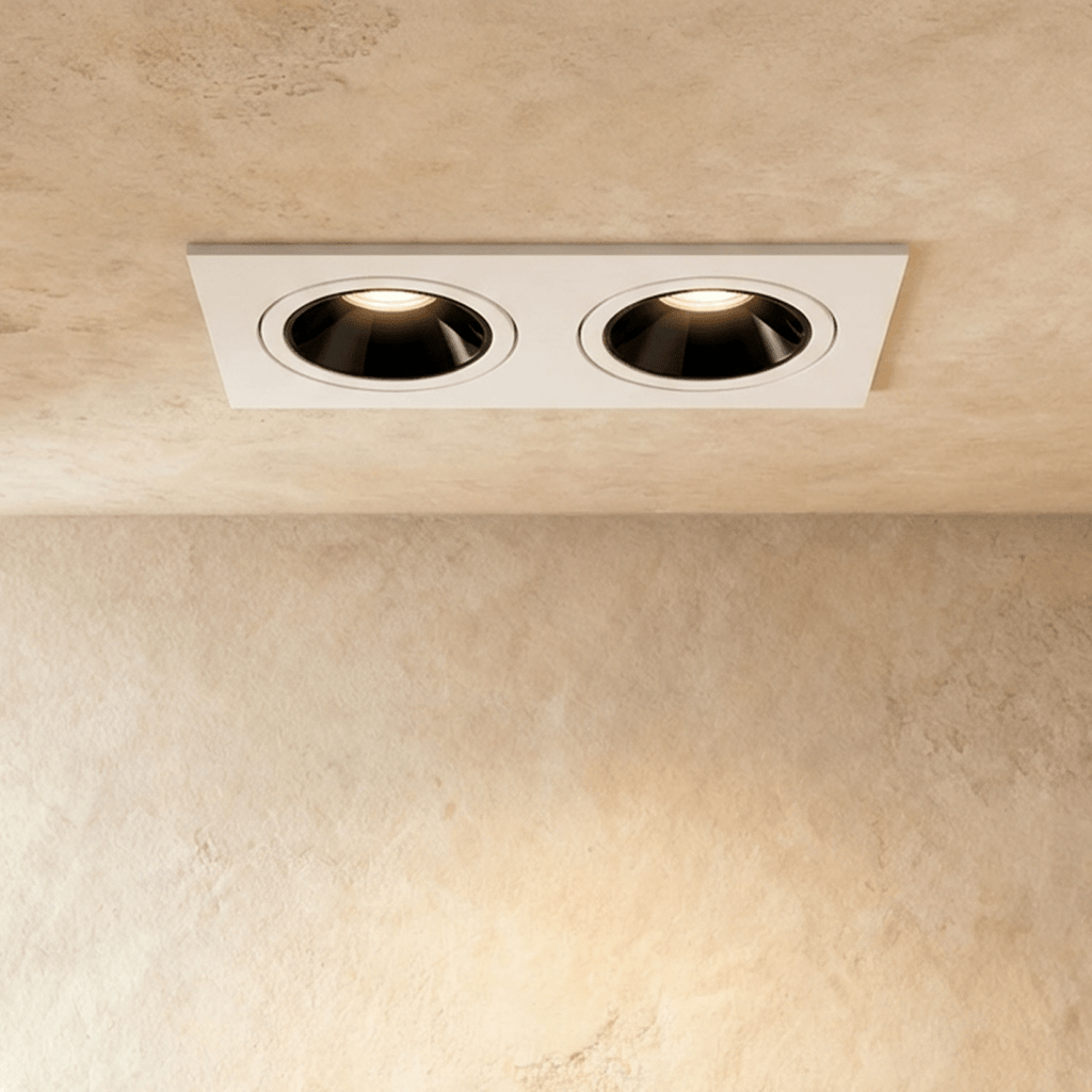 The Clérachic two-head recessed downlight in white, both tiltable heads glowing warm white against a plaster ceiling.