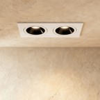 The Clérachic two-head recessed downlight in white, both tiltable heads glowing warm white against a plaster ceiling.