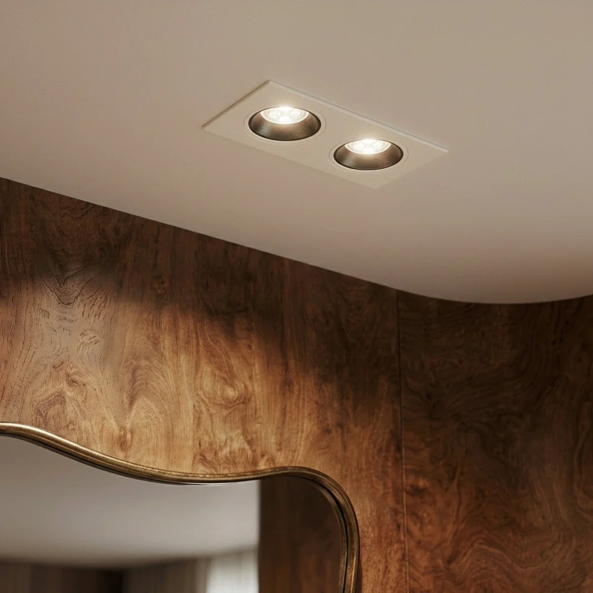 Close angle of the Clérachic white two-head recessed downlight glowing warm white beside a wood-panelled wall.
