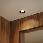 Close-up of the Clérachic white recessed downlight glowing warm white above a wood-framed doorway.