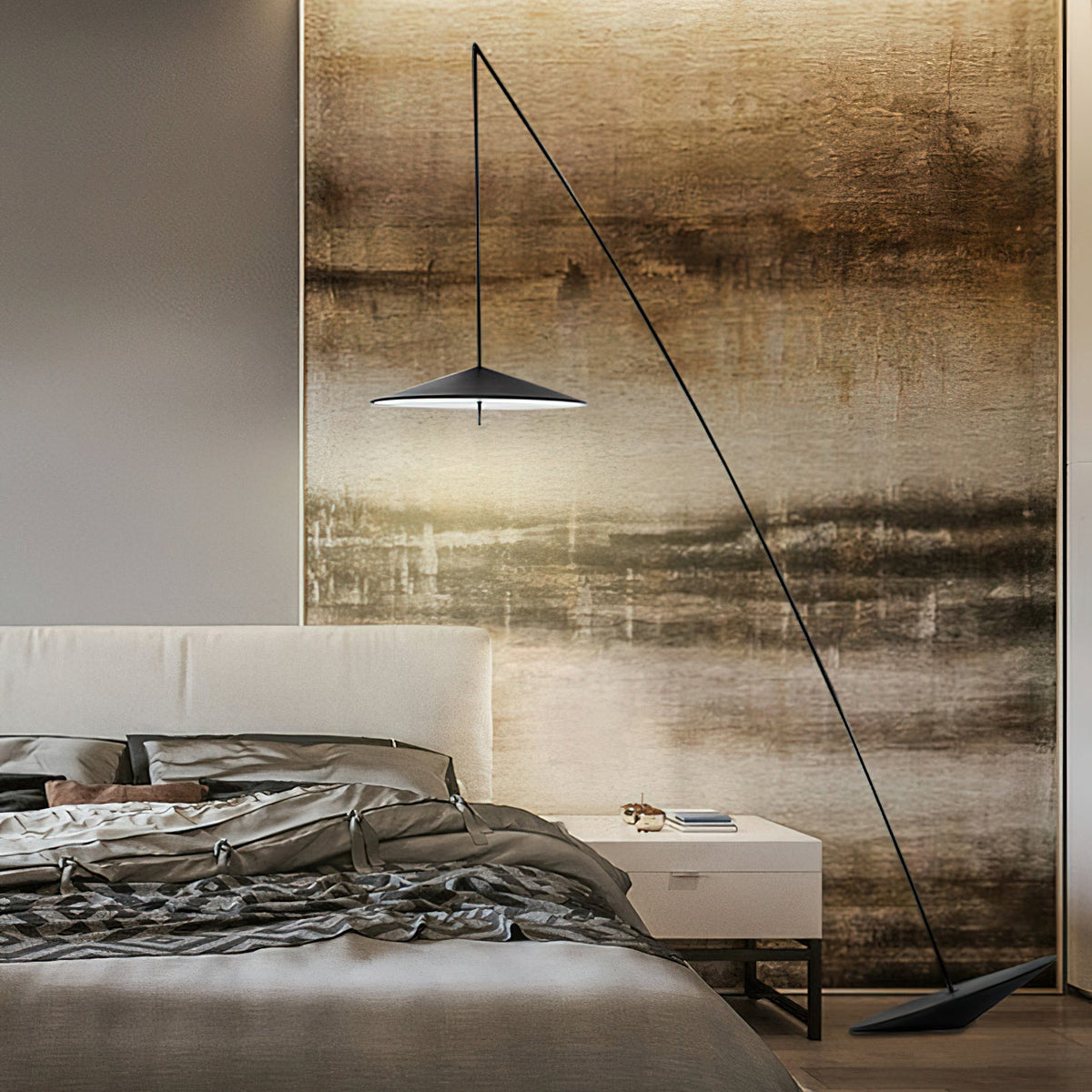 A black arc floor lamp hangs its disc shade in front of a painted landscape-style wall panel above a bed, from Clérachic.