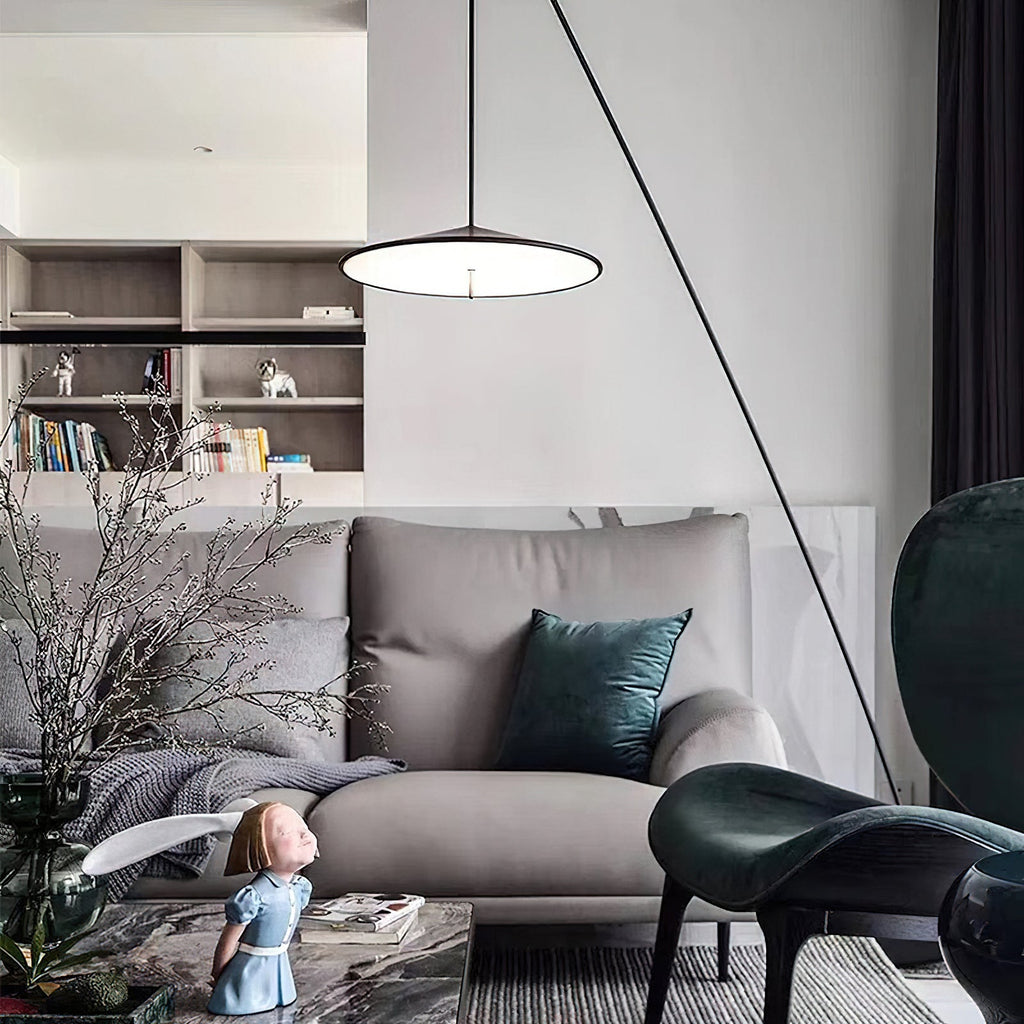 Lit disc shade hangs above a grey sofa with teal cushions, in a room with shelves, plants and a dark green chair, from Clérachic.