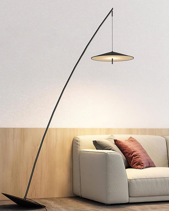 Warm light from the disc shade falls on a wood-panelled wall above a cream sofa with a rust cushion, a Clérachic floor lamp.