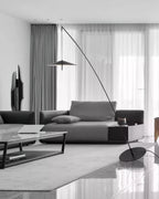 Greyscale room with sheer curtains, a dark sofa and a coffee table, and a slim black floor lamp leaning over them from Clérachic.