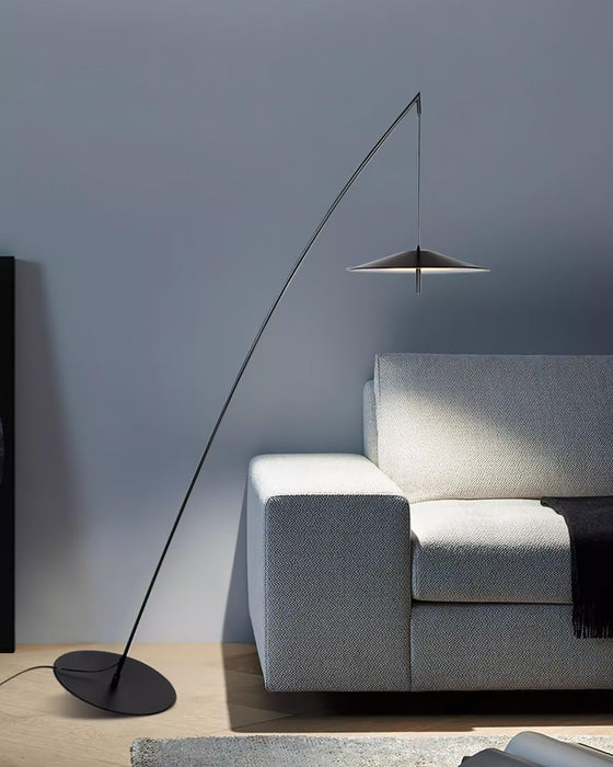 Pale grey sofa with a dark throw below the black stem and disc shade, against a blue-grey wall, from Clérachic.