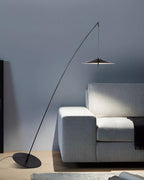 Pale grey sofa with a dark throw below the black stem and disc shade, against a blue-grey wall, from Clérachic.