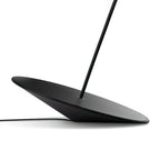 Angled base of this Clérachic floor lamp on a white surface, showing its black cord and stem rising from the centre.