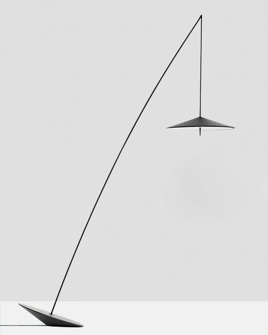 Black floor lamp with a long curved stem and a small disc shade, set on a tilted base against a pale grey backdrop, from Clérachic.