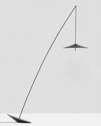 Black floor lamp with a long curved stem and a small disc shade, set on a tilted base against a pale grey backdrop, from Clérachic.