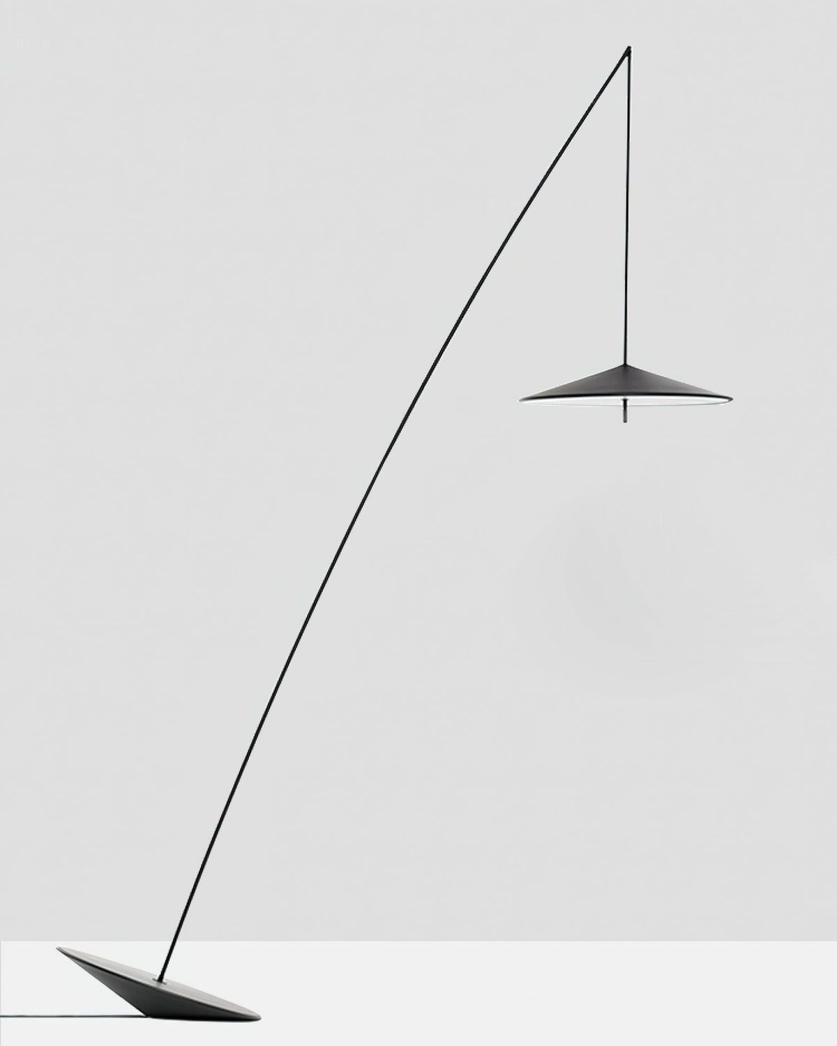 Black floor lamp with a long curved stem and a small disc shade, set on a tilted base against a pale grey backdrop, from Clérachic.