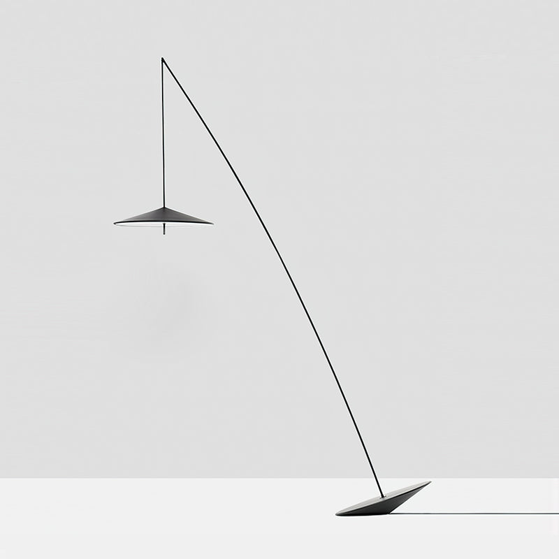 Full view of the black stem, disc shade and tilted base against a pale grey wall and floor, a Clérachic floor lamp.