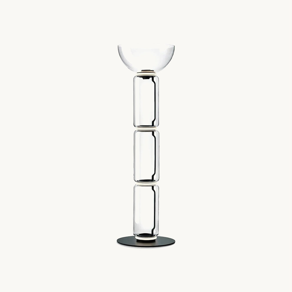Clérachic floor lamp on a plain white backdrop, three stacked clear glass cylinders topped by a wide glass bowl on a round black base.
