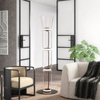 Lit Clérachic floor lamp with a flared glass top, between a black-framed armchair and a cream sofa chair, in front of steel-framed glass doors.