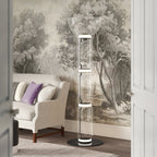 Clérachic floor lamp in front of a tree-patterned wall mural, beside a cream armchair with a lilac cushion and a wood floor.