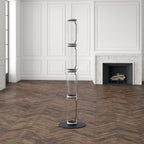 Unlit Clérachic floor lamp of four stacked glass cylinders in a white panelled room with a marble fireplace and herringbone floor.