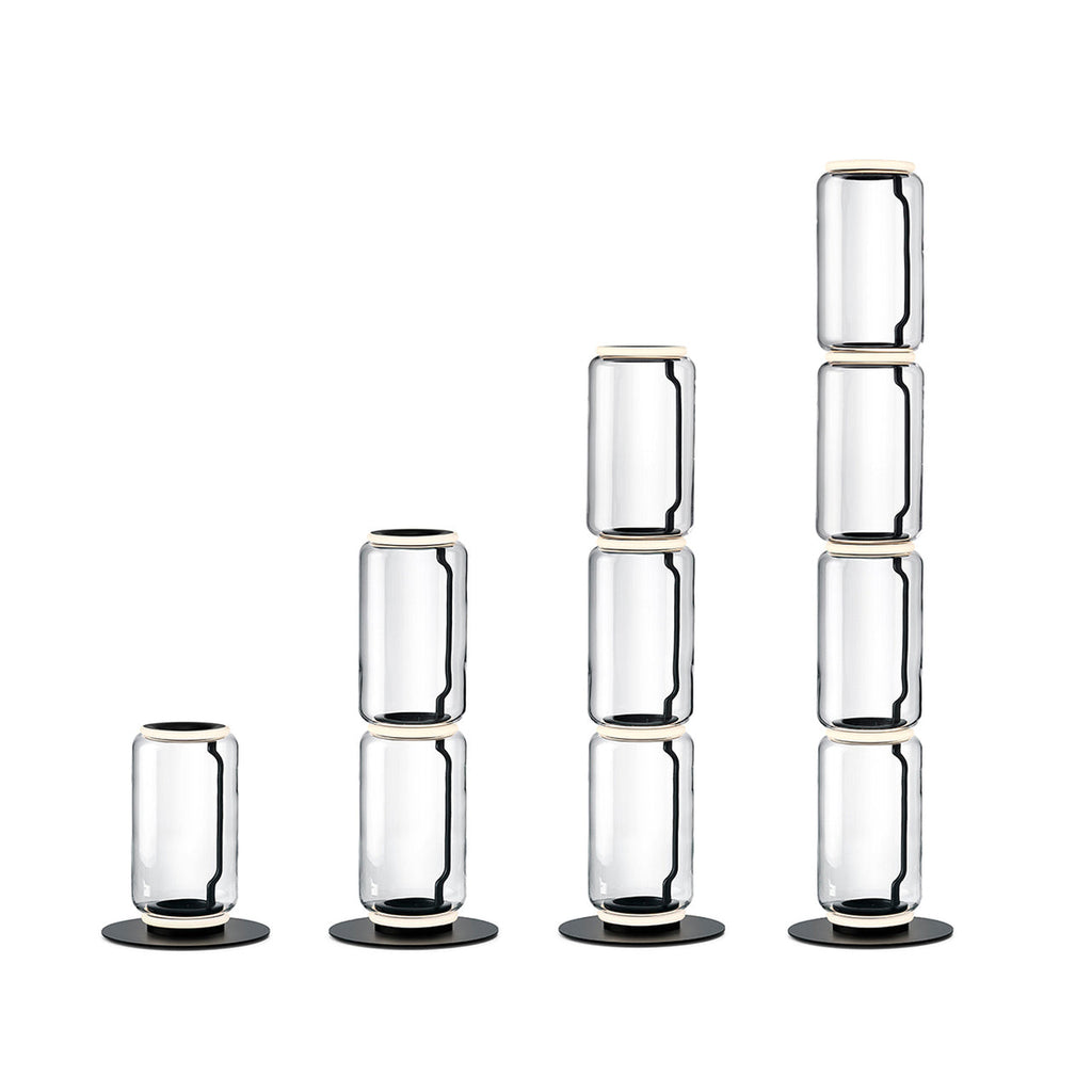 Four Clérachic floor lamps in rising heights on white, built from one to four stacked glass cylinders with round black bases.