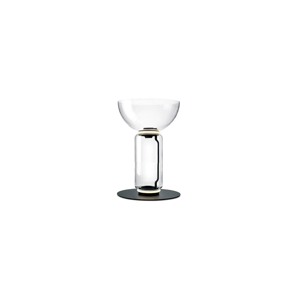 Short Clérachic floor lamp on white, a clear glass cylinder under a wide glass bowl, on a round black base.