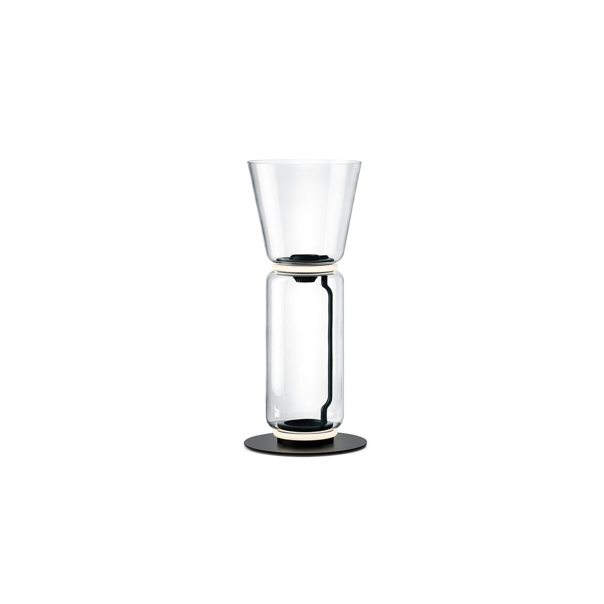 Clérachic floor lamp on white, a clear glass cylinder under a tall flared glass top, on a round black base.