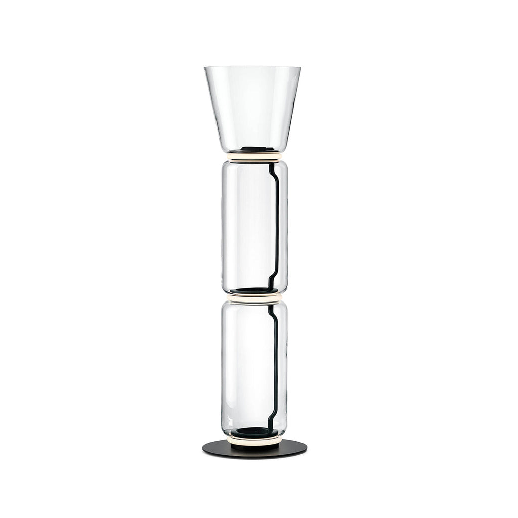 Clérachic floor lamp on white, two clear glass cylinders under a tall flared glass top, on a round black base.