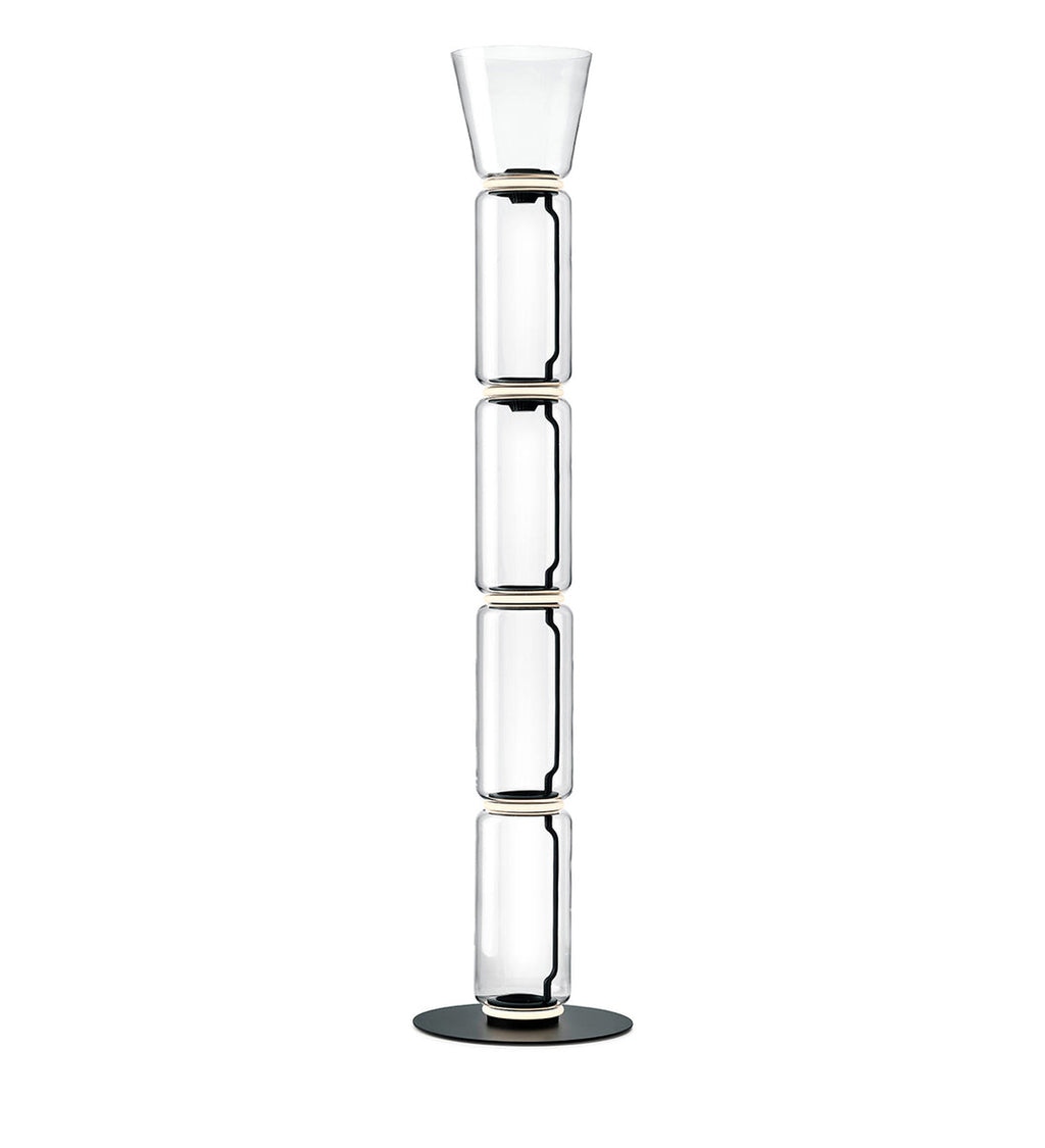 Tall Clérachic floor lamp on white, four glass cylinders under a narrow flared glass top, on a round black base.