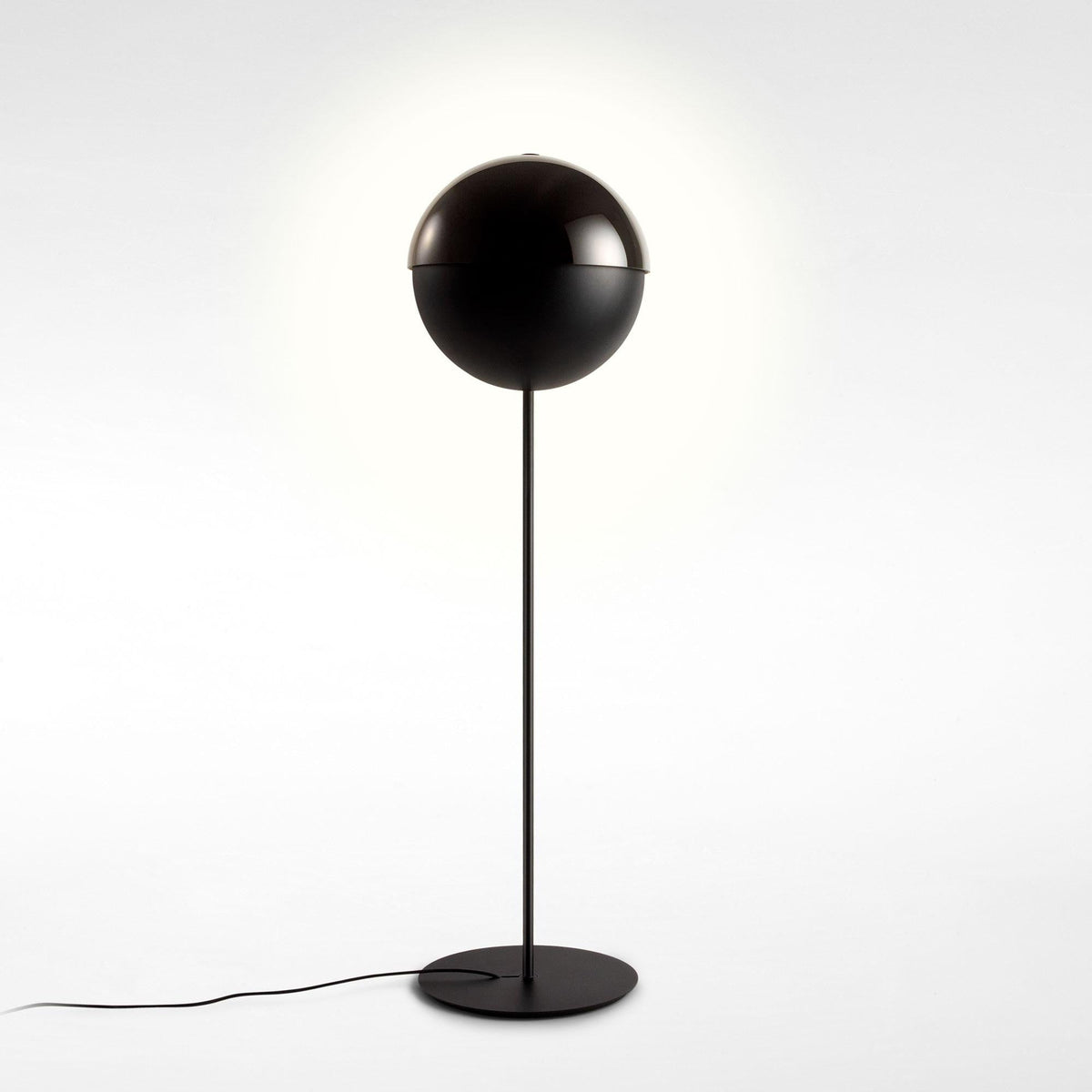 Black floor lamp with its dome closed into a full sphere on a thin stem, on a soft white backdrop; this Clérachic design.
