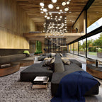 Broad view of a modern lounge with a low grey sofa, a timber-clad ceiling and pendant lights; the Clérachic lamp is far behind.