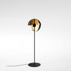 Clérachic black floor lamp with its dome turned partly down, a bronze outer shell over a frosted inner globe, on a light grey backdrop.