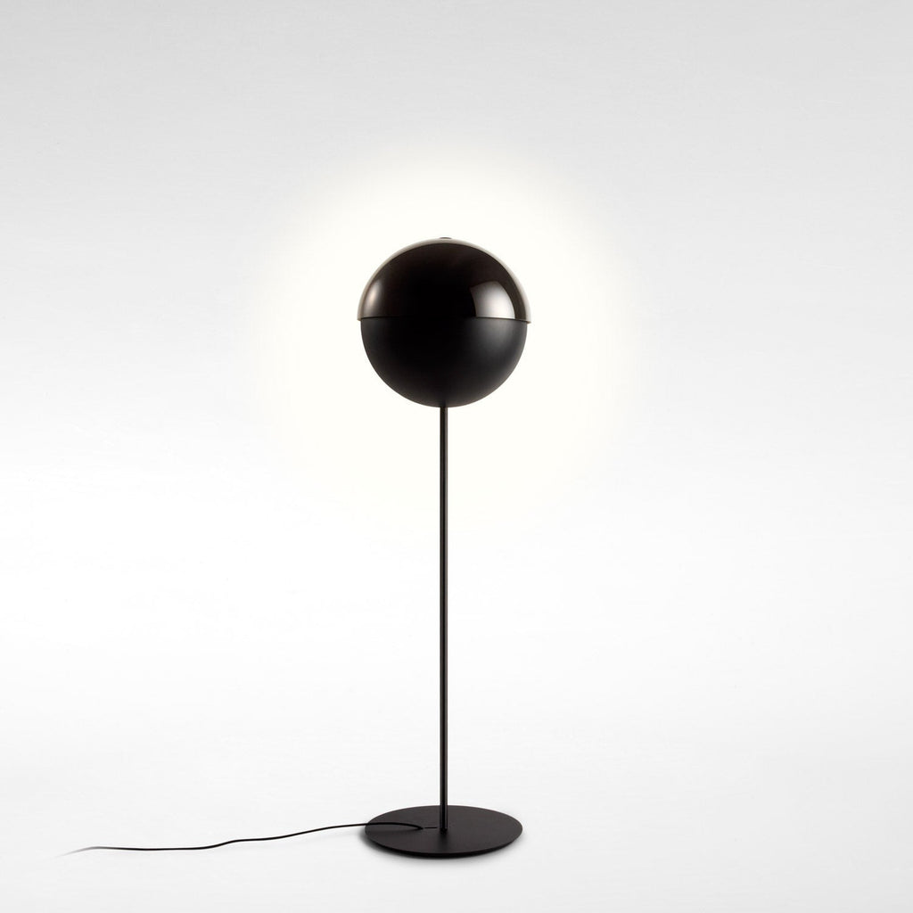 Closed black sphere shade on a slim stem, with a faint halo of light behind it, on a pale studio backdrop; a Clérachic floor lamp.
