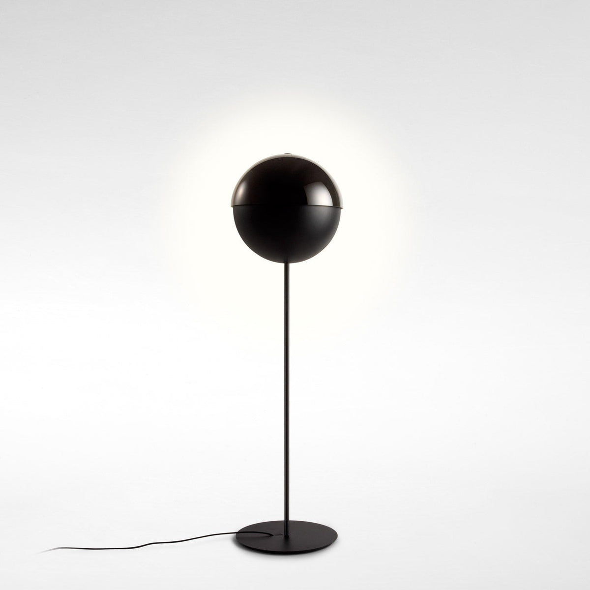 Closed black sphere shade on a slim stem, with a faint halo of light behind it, on a pale studio backdrop; a Clérachic floor lamp.