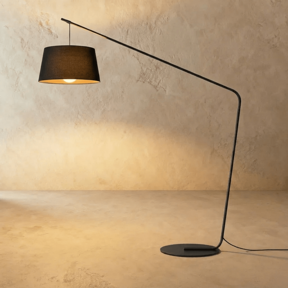 Clérachic arc floor lamp with a black tapered fabric shade, a long slim black arm and a round flat base on limewash.