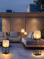Clérachic lanterns lit on a stone terrace at dusk, with a slatted wall and a grey sofa behind.