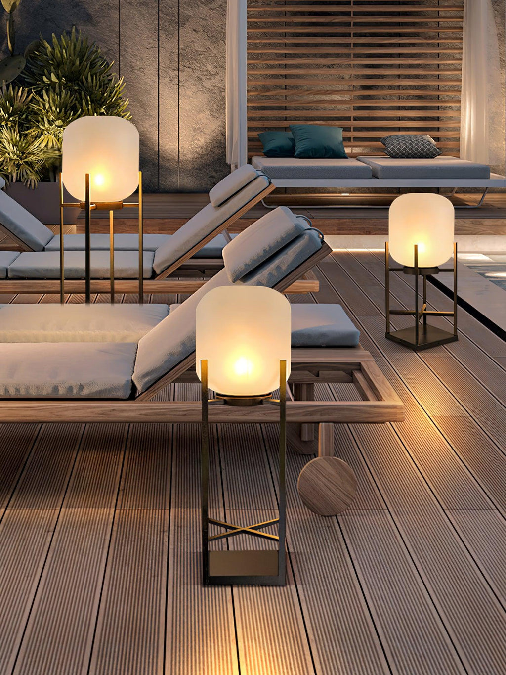 Clérachic lanterns glowing on a timber deck around wooden sun loungers at dusk, with a slatted screen behind.