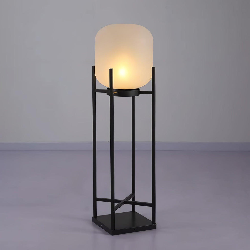 This Clérachic lantern lit on a grey studio floor against a lilac-grey wall, with a frosted shade on a black frame.